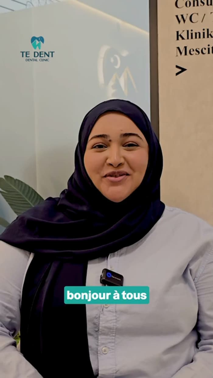 A woman speaking to camera inside the TE Dent clinic, the treatment-room signs behind her